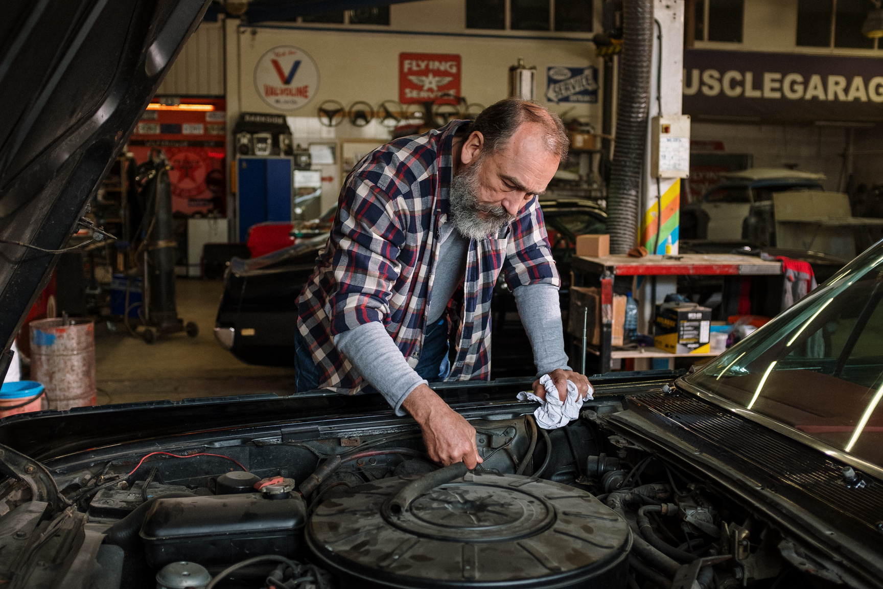 Man in Red White and Black Plaid Dress Shirt Holding Black Car